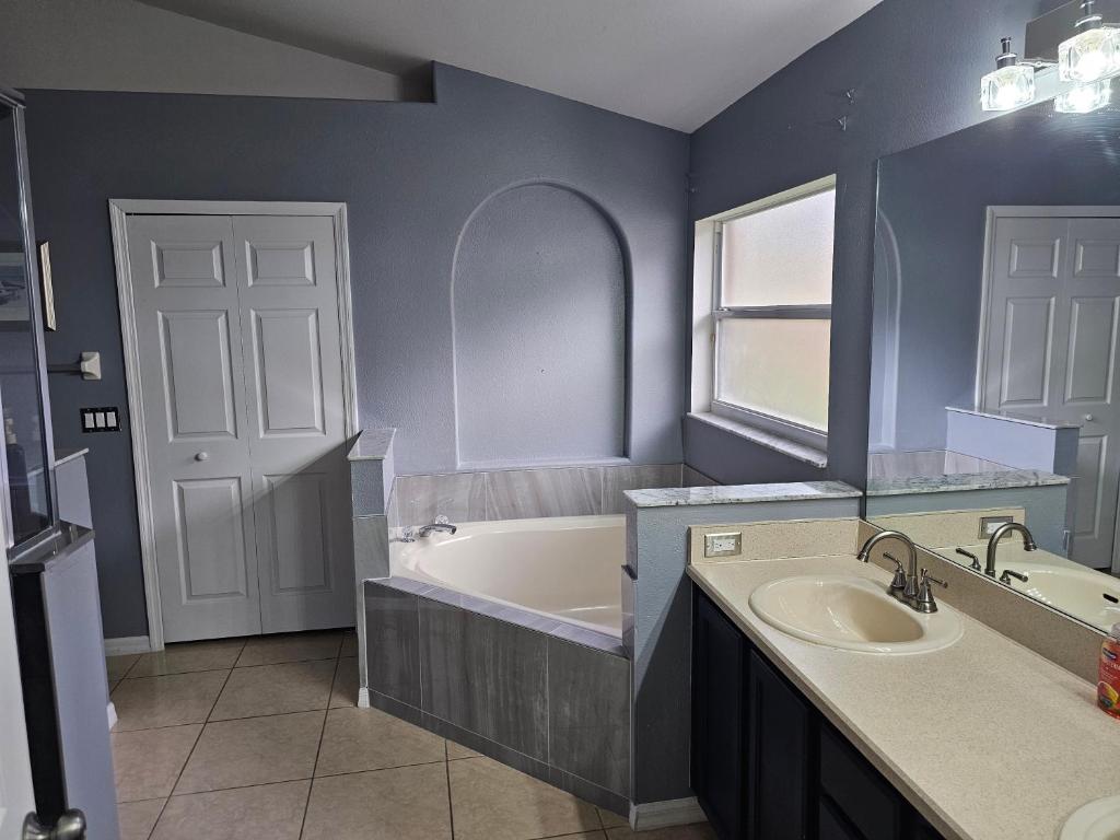 a bathroom with a tub and a sink and a mirror at Minnie Heaven in Kissimmee