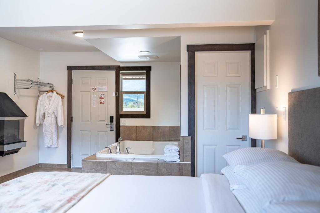a bedroom with a bed and a bath tub at Swiss Chalet Motel in Revelstoke