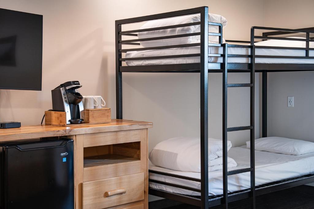 a room with two bunk beds and a desk with a computer at Swiss Chalet Motel in Revelstoke