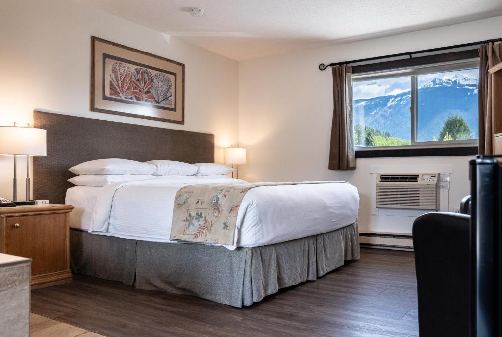 a hotel room with a bed and a window at Swiss Chalet Motel in Revelstoke