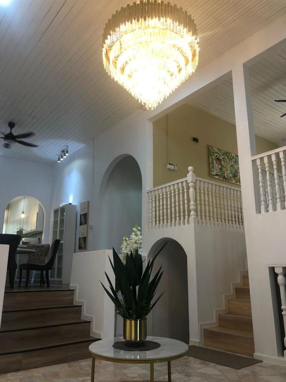 a lobby with a chandelier and a table with flowers on it at Calma Villa Jalan Sultanah in Alor Setar