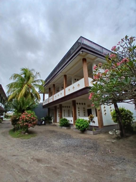 un edificio con una palmera delante en Lamancha Homestay, en Kuta Lombok