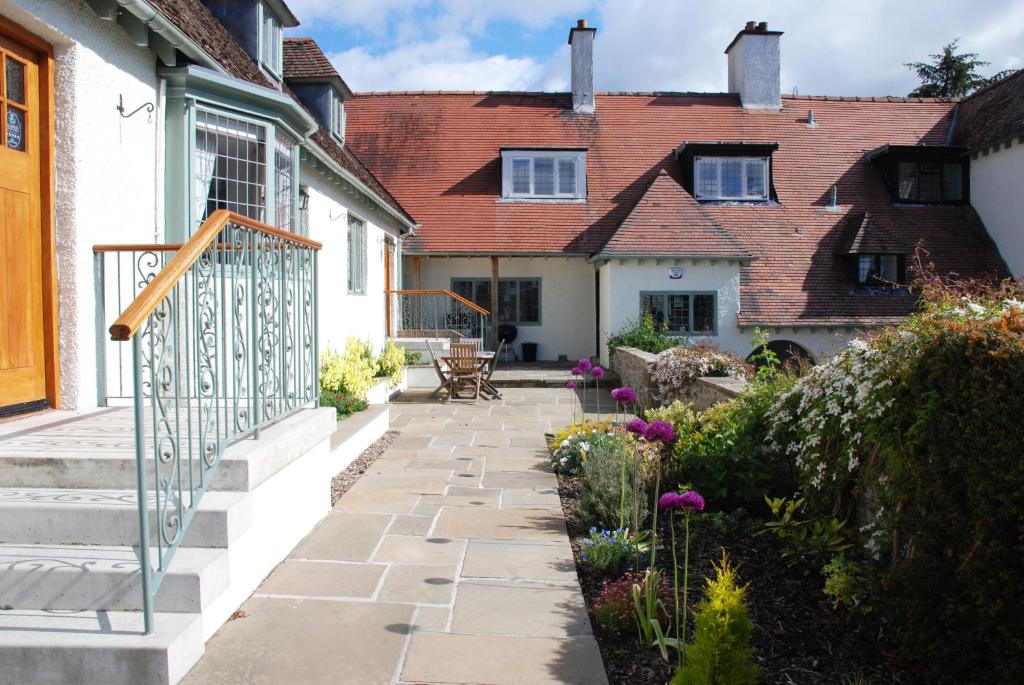 un jardín con una pasarela de piedra frente a una casa en Sandford Country Cottages, en Newport-On-Tay