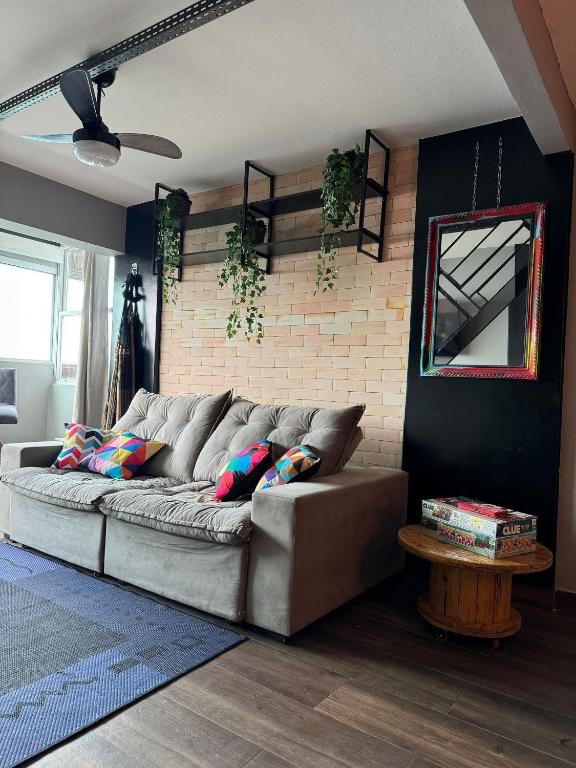 a couch in a living room with a brick wall at Apartamento Sunset House Porchat in São Vicente