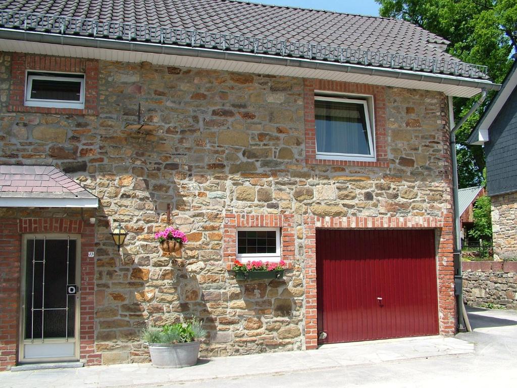 un edificio de ladrillo con una puerta roja y dos ventanas en The Cottage and The Loft, en Amblève