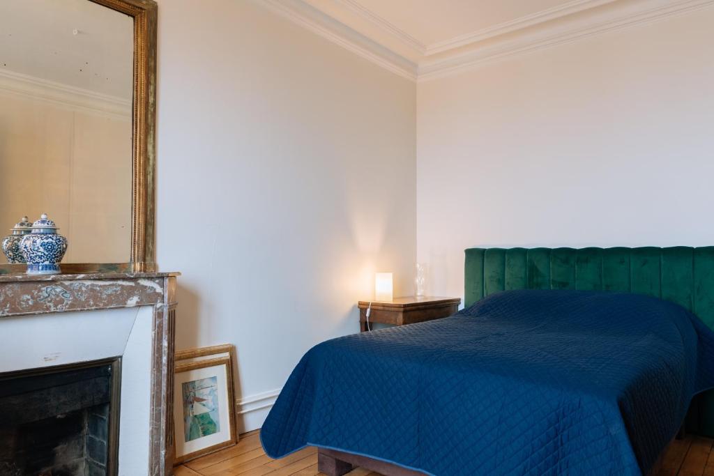 une chambre avec un lit bleu et un miroir dans l'établissement Stylishly Decorated 2BD Apartment Montmatre!, à Paris