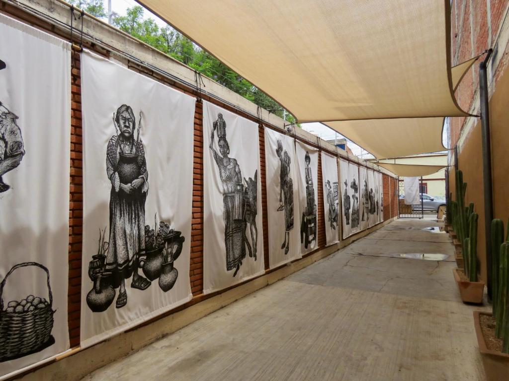 a hallway with a row of paintings on the wall at Hostal Centro Histórico in Oaxaca City