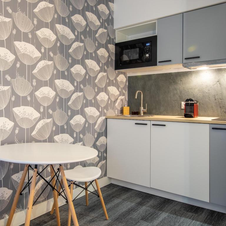 une cuisine avec des armoires blanches et une table dans l'établissement New Studio Near Bois de Vincennes, à Paris
