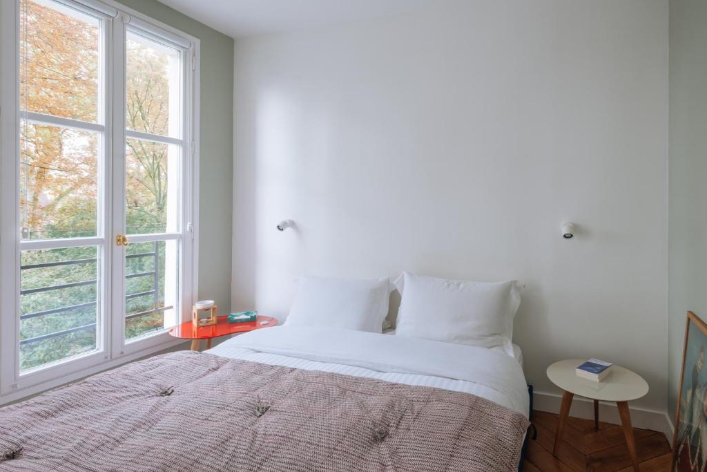 une chambre blanche avec un lit et une fenêtre dans l'établissement Modern Rustic-style Apartment 7th arrondissement!, à Paris