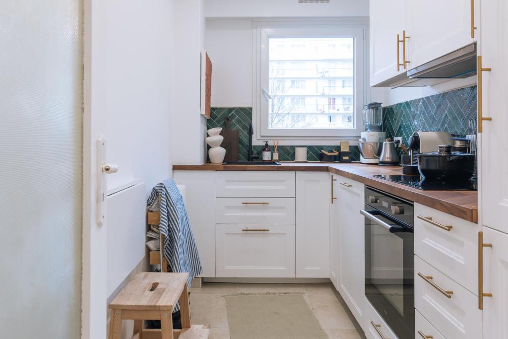 une cuisine avec des armoires blanches et une fenêtre dans l'établissement Beautiful 1BD Apartment Issy-les-Moulineaux!, à Issy-les-Moulineaux