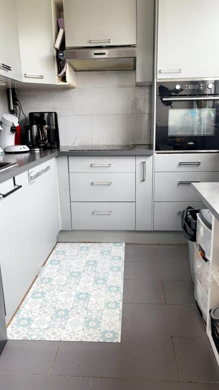 une cuisine avec des armoires blanches et un sol carrelé dans l'établissement Magnifique appartement, à Stains