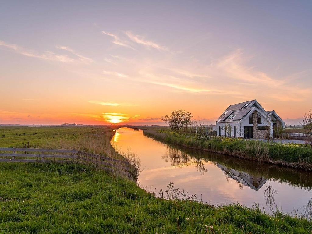 a barn on the side of a river at sunset at Getaway with Bubble Bath in Oudeschild
