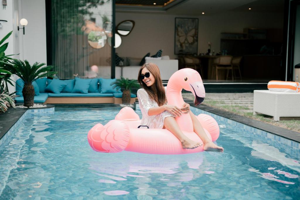 a woman sitting on an inflatable flamingo in a swimming pool at Seminyak vila luxury 4Br near beach LAfavela in Seminyak