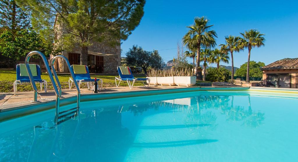basen z niebieskimi krzesłami i palmami w obiekcie Vignette Collection Finca Banyols by IHG w mieście Alaró