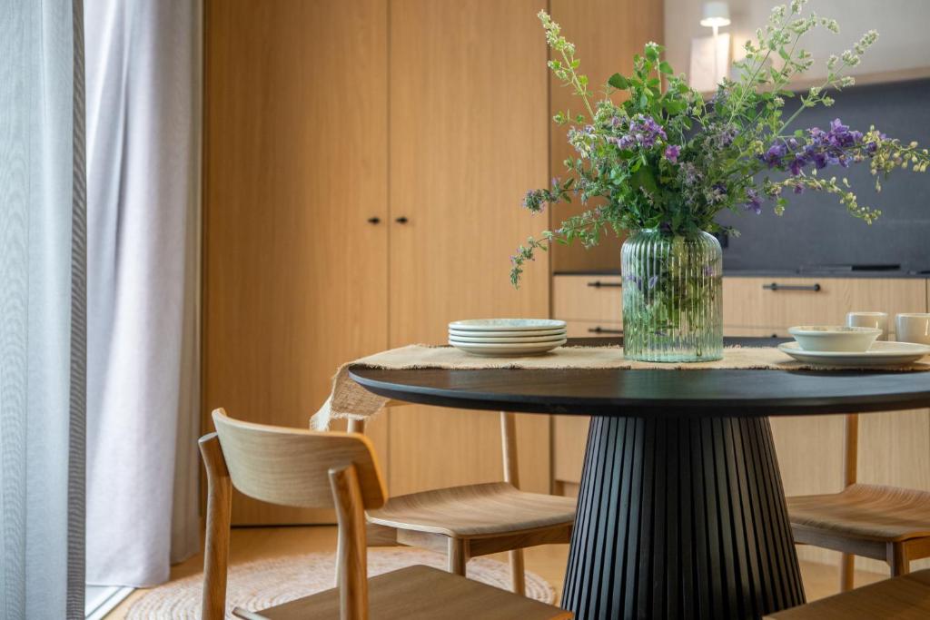a dining room table with a vase of flowers on it at 50 meters to the Sea in Juodkrantė