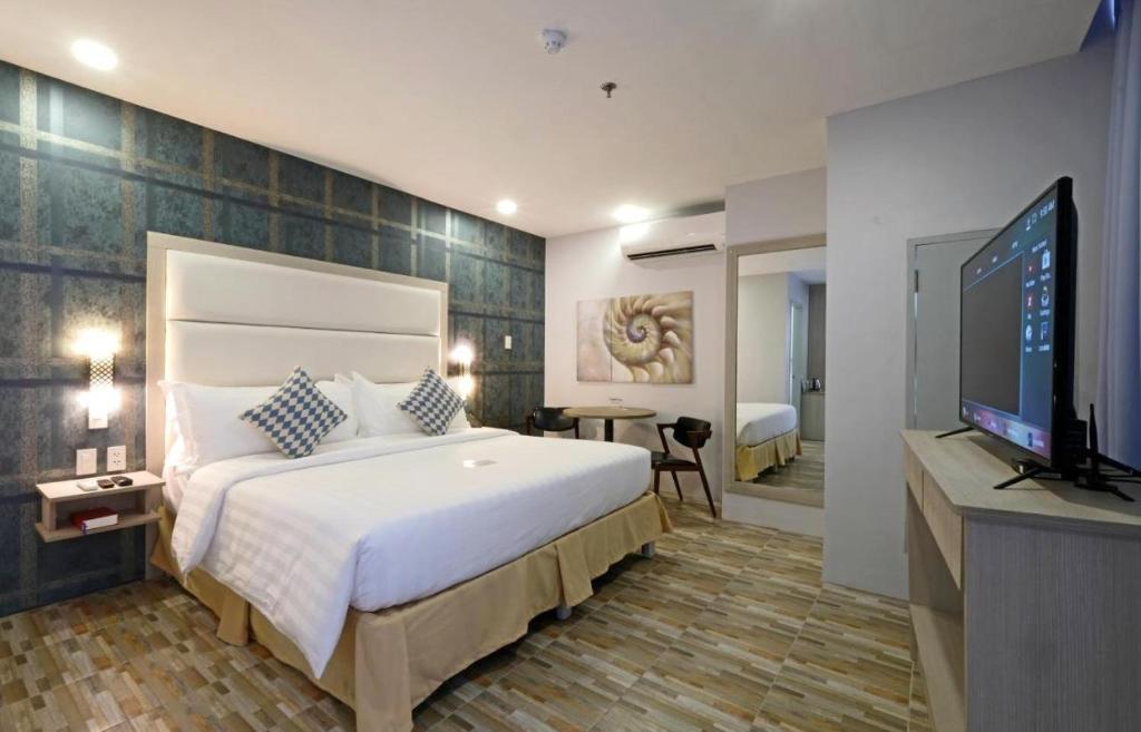 a bedroom with a large bed and a flat screen tv at Amethyst Boutique Hotel Cebu powered by Cocotel in Cebu City