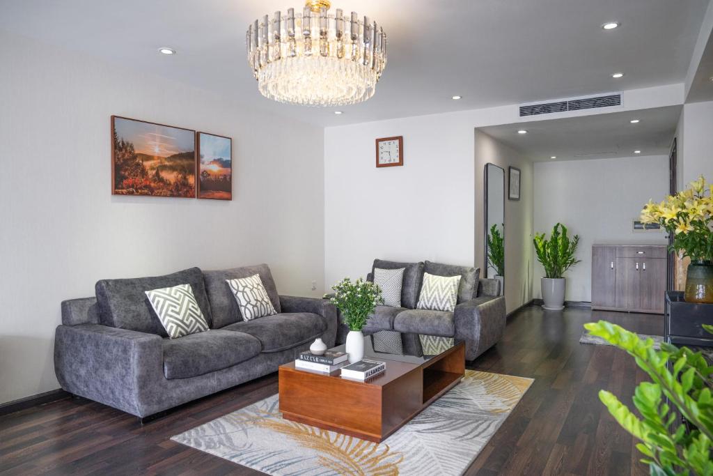 a living room with two couches and a chandelier at Viet Vuong Building Ha Noi Capital in Hanoi