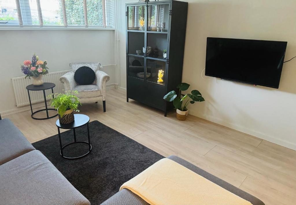 een woonkamer met een bank en een flatscreen-tv bij Souterrain Boslaan Katwijk aan zee in Katwijk aan Zee