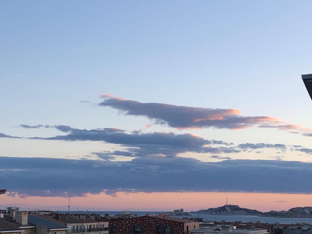 un ciel nuageux au-dessus d'une ville au coucher du soleil dans l'établissement Bel appartement avec vu mer, à Marseille