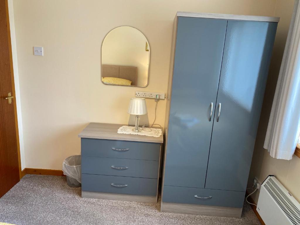 a bedroom with a blue cabinet and a mirror at Riverside in Tarbert