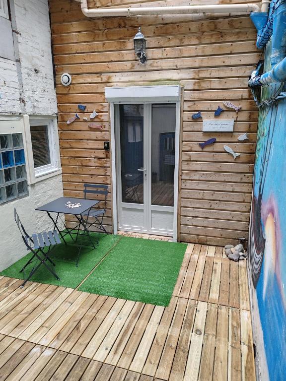 un patio avec une table et une porte sur une cabane dans l'établissement les petits poissons dans l eau, à Mers-les-Bains