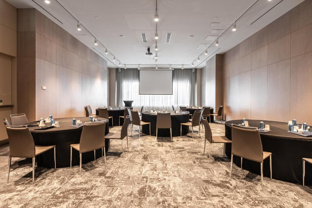 A conference room set with round tables, a projection screen and presentation equipment.