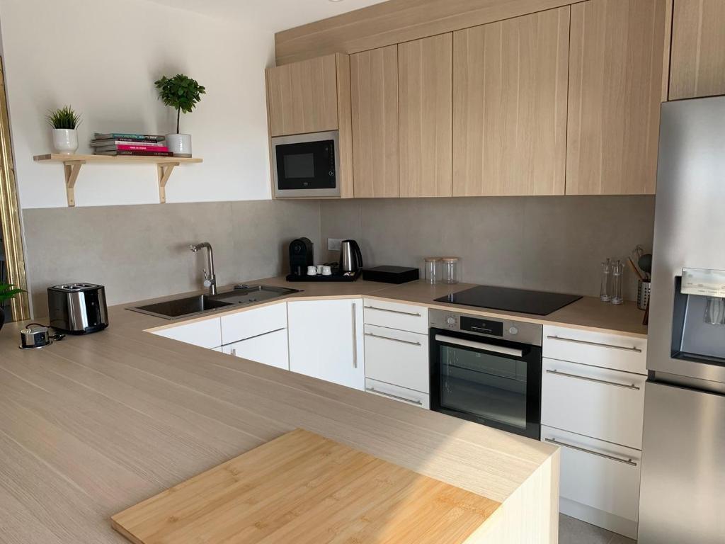 une cuisine avec des armoires blanches et des appareils en acier inoxydable dans l'établissement 4 pièces Luxe - Accès Piscine, à Cagnes-sur-Mer