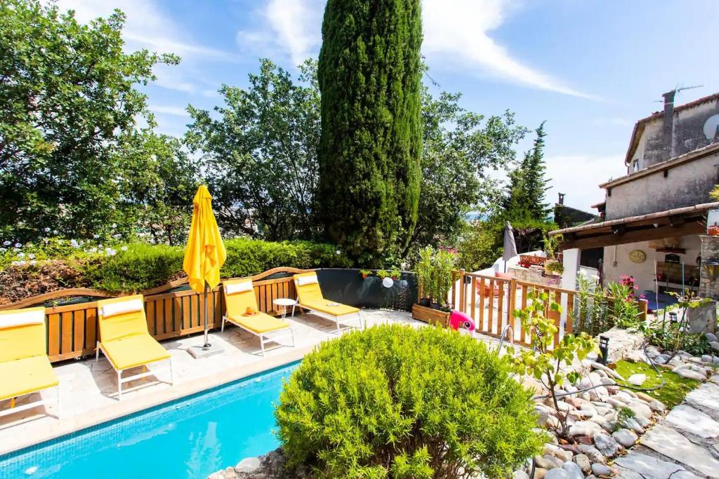 une terrasse avec des chaises jaunes et une piscine dans l'établissement Lovely old town house sea view, 1br AC, pool,sauna, à Cagnes-sur-Mer