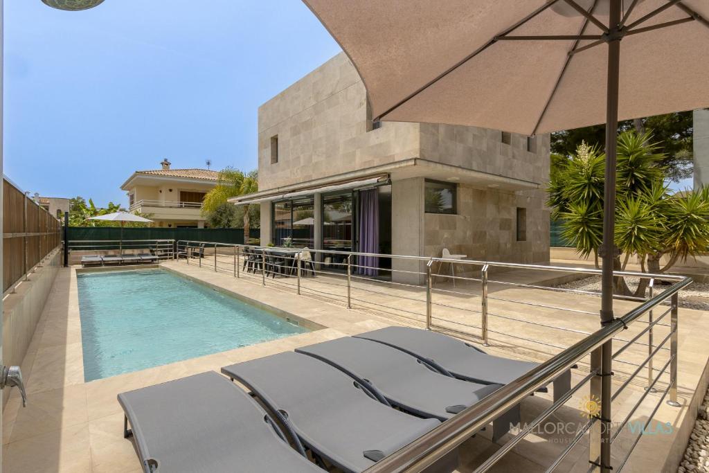 a pool with chairs and an umbrella next to a house at Villa Iola a 150m de la playa ideal para familias y amigos in Playa de Muro