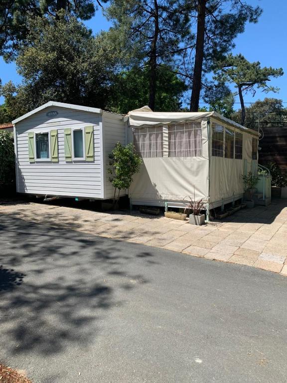 une maison blanche avec une tente dans une allée dans l'établissement Mobilhome a 5 min de la mer à pied camping 5etoiles, à Saint-Georges-de-Didonne