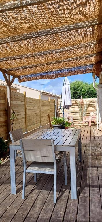 une terrasse en bois avec une table de pique-nique et un parasol dans l'établissement Le confort proche de l'étang, à Marseillan