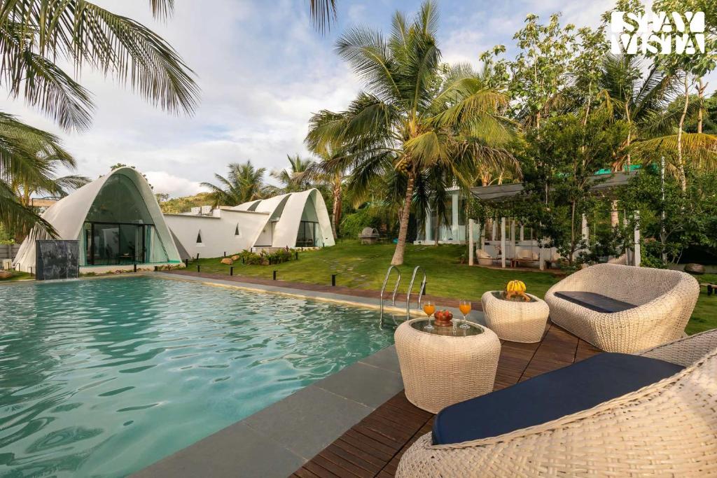 a resort swimming pool with chairs and a tent at StayVista at Shwaas 4BR Mysore with Private pool and landscape in Mysore
