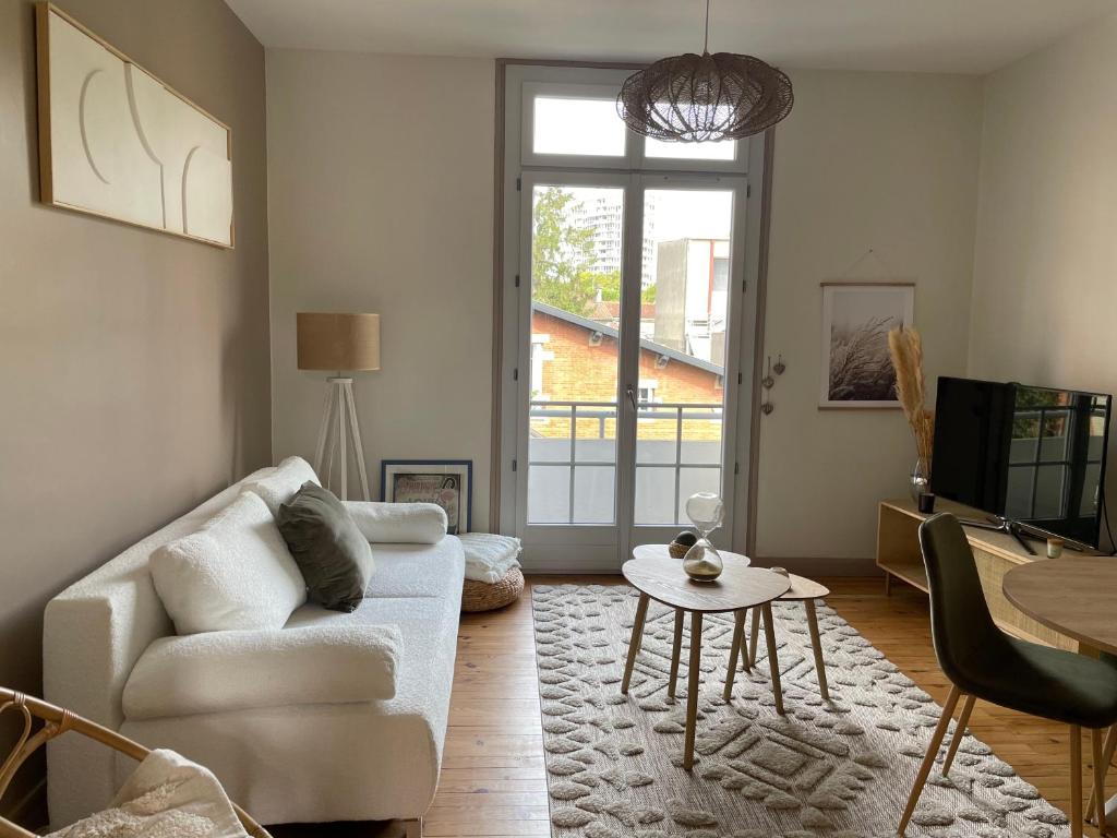 un salon avec un canapé blanc et une table dans l'établissement Coeur de Toulouse, appartement paisible et charmant, à Toulouse