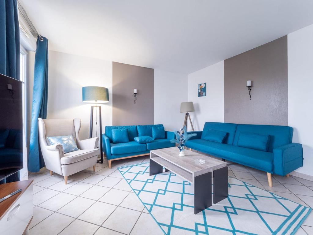 - un salon avec des canapés bleus et une table basse dans l'établissement Appartement Serris- Val d'europe -Disney, à Serris