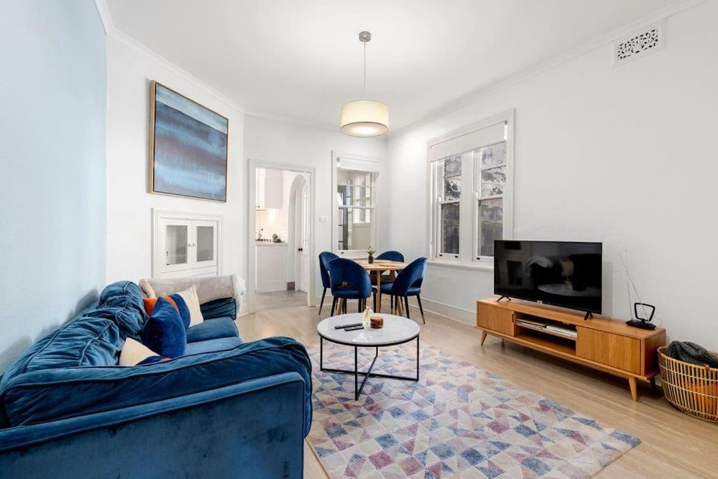 een woonkamer met een blauwe bank en een tv bij Vacation Home w Private Rooftop and Harbour View in Sydney