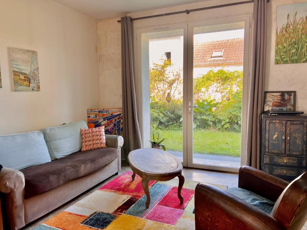 un salon avec un canapé, une table et une fenêtre dans l'établissement Maison briarde 4/6 personnes proche Disney, à Crécy-la-Chapelle