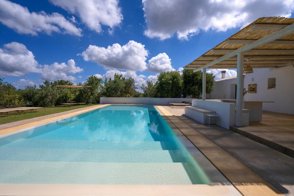 une piscine avec une pergola et une maison dans l'établissement Villa Eva, villa privata con piscina a sfioro, à Ostuni