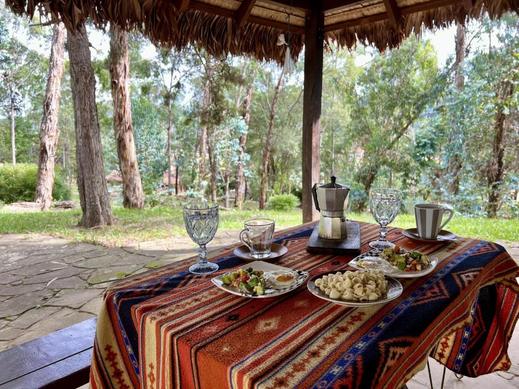 a table with plates of food and glasses on it at Valle Verde Lodge - Bosque in Samaipata