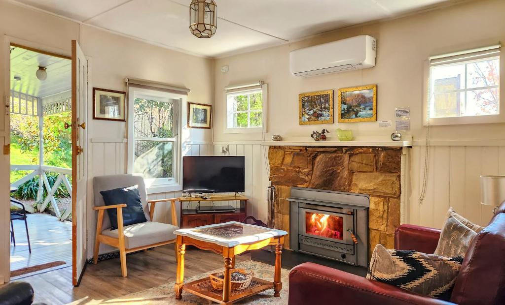 a living room with a fireplace and a tv at Bonnie Brae Cottage in Hepburn Springs
