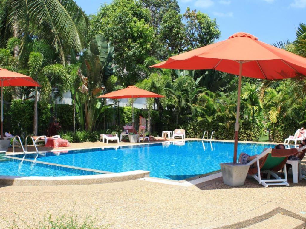 a swimming pool with a red umbrella and chairs at Wild Orchid Villa Krabi in Ao Nam Mao