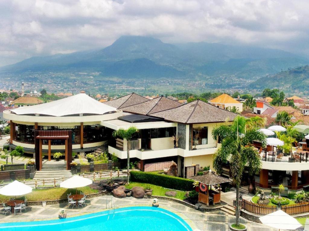 a resort with a pool and a mountain in the background at Purnama Hotel in Malang