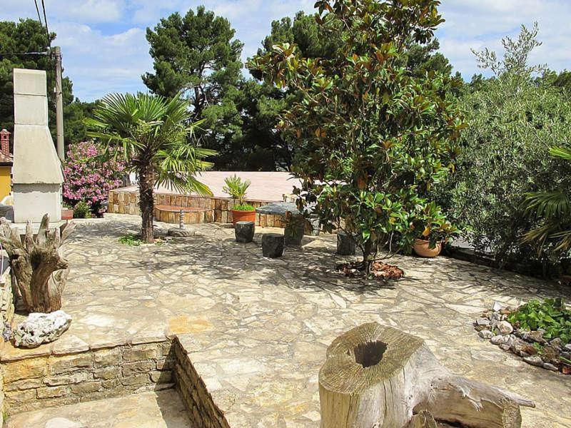 a garden with trees and a stone patio at Holiday Home Kastel in Kaštel