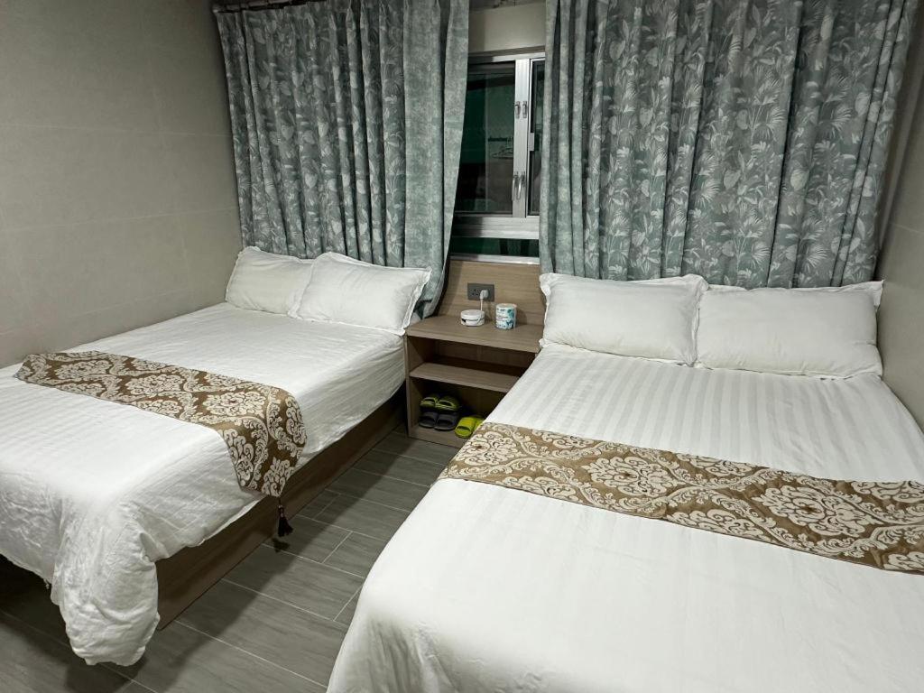 a hotel room with two beds and a window at New Star Guest House in Hong Kong