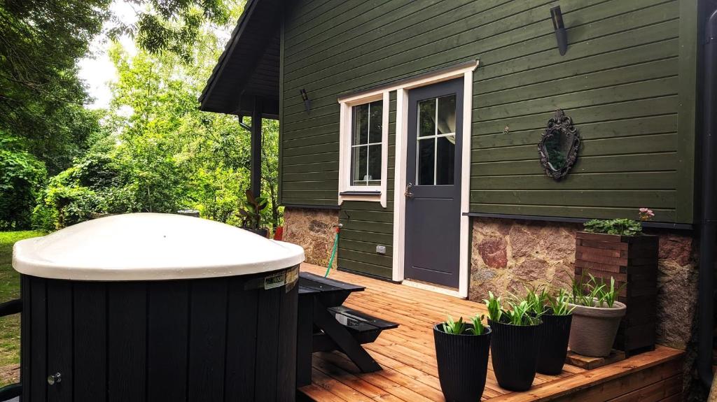 a green house with a hot tub on a wooden deck at Svečių namelis KNYGŲ NAMAS in Kelmė