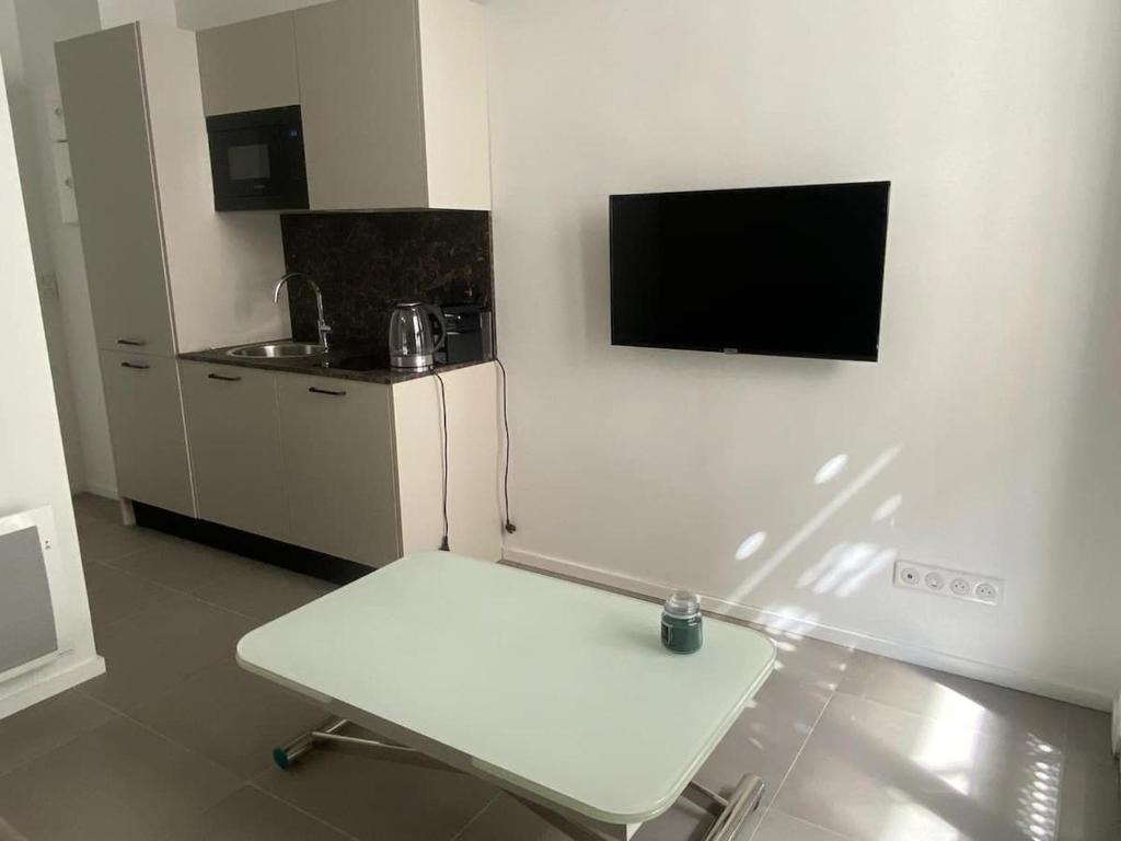 une chaise blanche dans une pièce avec une télévision au mur dans l'établissement VILLA ANGELUS 2 minutes de Monaco, à Beausoleil