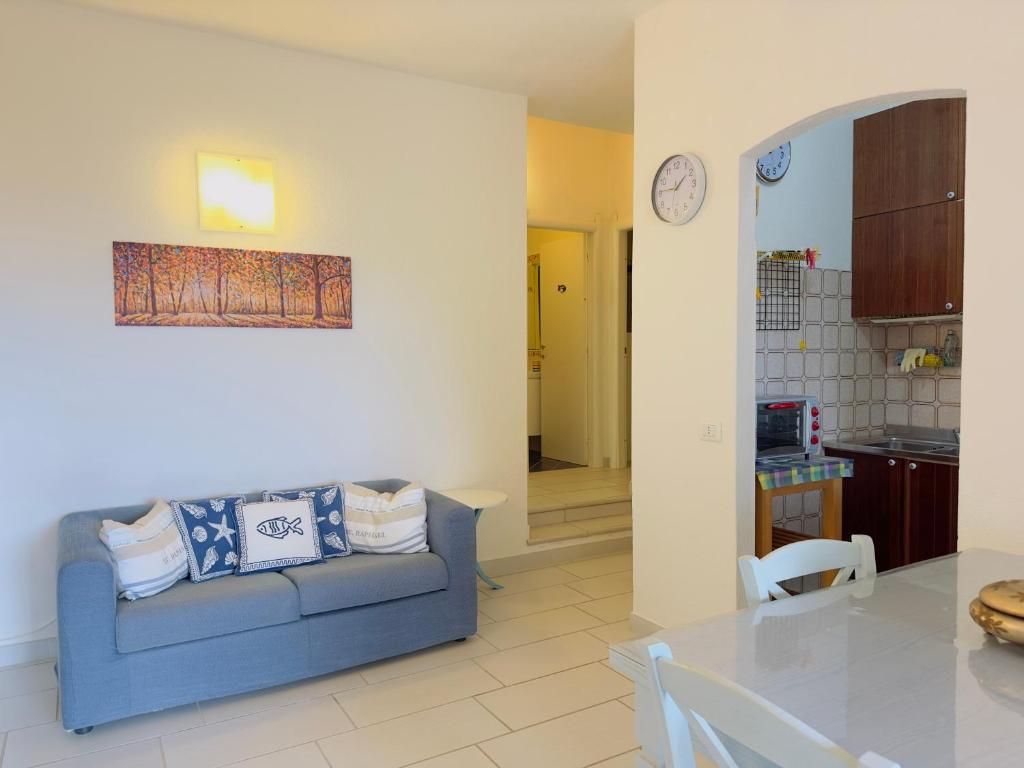 uma sala de estar com um sofá azul e uma mesa em VILLA FERRATA - A soli 300m dal mare em Costa Rei