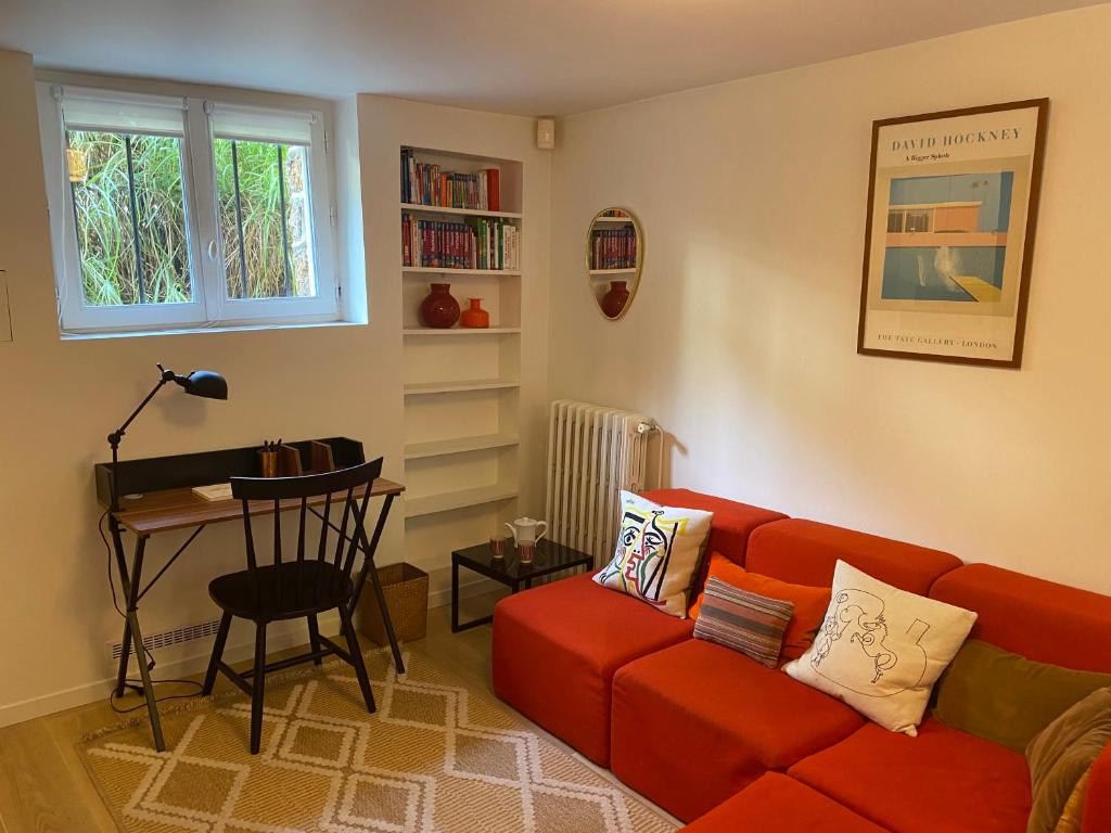 a living room with a red couch and a table at Appartement privé avec jardin in Boulogne-Billancourt