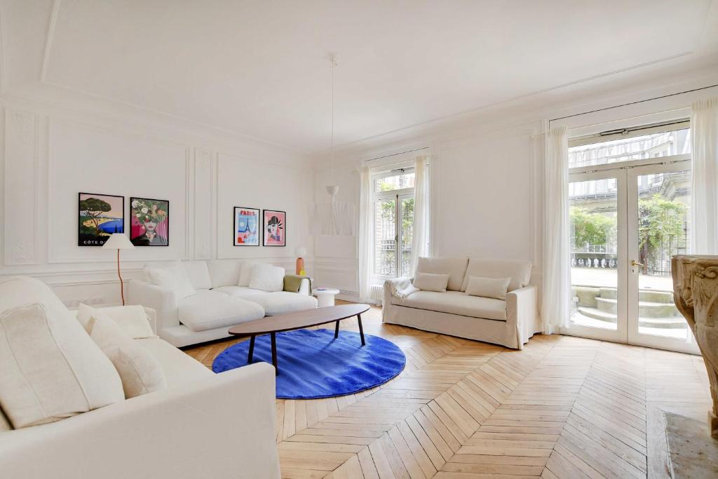 - un salon doté d'un mobilier blanc et d'un tapis bleu dans l'établissement Chic flat with garden terrace -4BR-12P - Trocadéro, à Paris