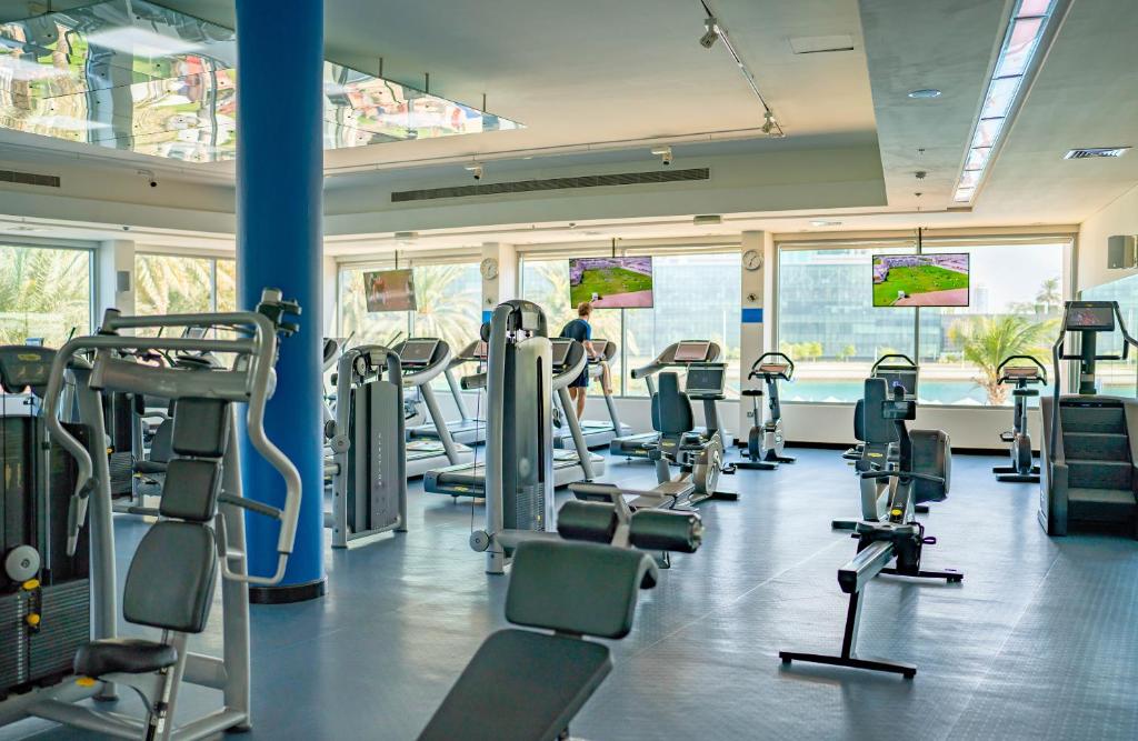 a gym with rows of treadmills and ellipticals at Beach Rotana - Abu Dhabi in Abu Dhabi