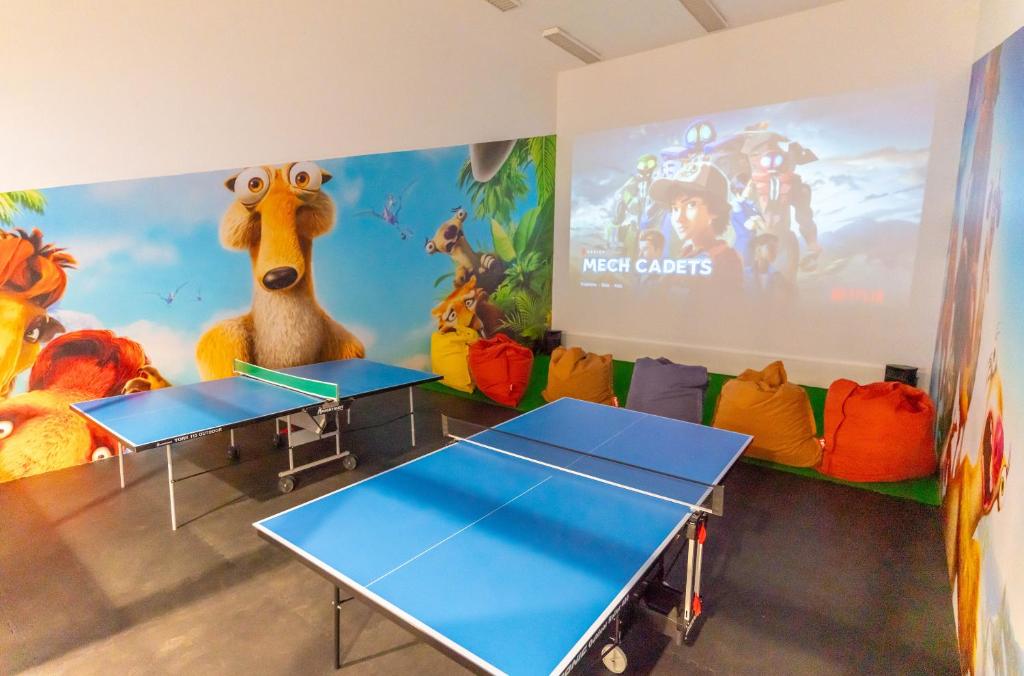 a classroom with two ping pong tables and a large screen at Beach Rotana - Abu Dhabi in Abu Dhabi